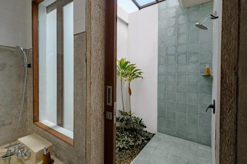 a bathroom with a shower and a glass door at Uddhara Ubud Villa in Ubud