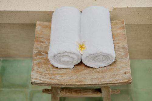 a wooden chair with towels and a flower on it at Uddhara Ubud Villa in Ubud