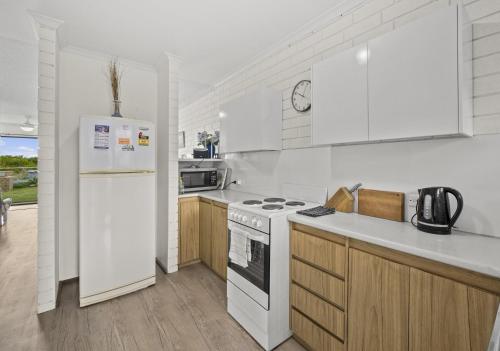 a kitchen with white appliances and wooden cabinets at Sun & Surf Aldinga Beach Apartment in Aldinga Beach