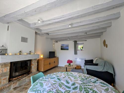 a living room with a table and a fireplace at Maison confortable avec jardin clos, wifi et parking, idéale pour se ressourcer en pleine nature - FR-1-591-612 in Mézières-en-Brenne