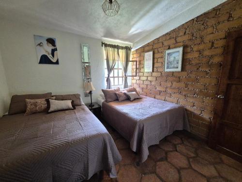 a bedroom with two beds and a brick wall at La Cabaña Zacatlán in Zacatlán