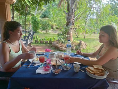 two women sitting at a table eating food at Jungle Eco Lodge & Safari in Sigiriya