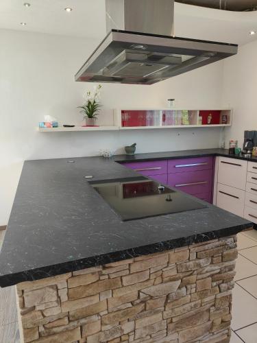 a kitchen with a granite counter top and purple cabinets at Ferienwohnung Dorfleben, nahe Jennersdorf und Therme in Windisch Minihof