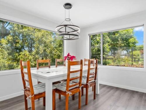 a dining room with a white table and chairs and windows at Fantail Haven in Kinloch