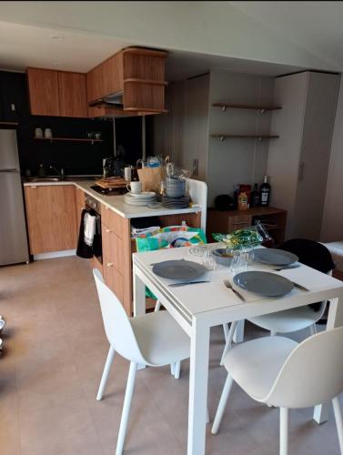 - une cuisine avec une table blanche et des chaises blanches dans l'établissement Siblu le Montourey frejus, à Fréjus
