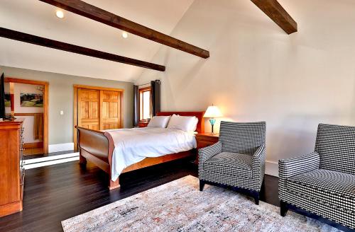 a bedroom with a bed and two chairs at Beartopia- Hot Tub, Views, 2 Primary Suites! in Killington