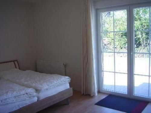 une chambre avec un lit et une grande fenêtre dans l'établissement Bungalow Meeresbrise mit WLAN, à Butjadingen
