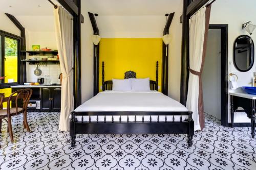 - une chambre avec un lit et un mur jaune dans l'établissement Rosie Countryside villa- 1BR retreat, à Hiếu Nhơn