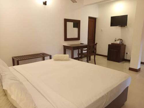 a bedroom with a bed and a desk and a television at Hikka Sands & SPA in Hikkaduwa