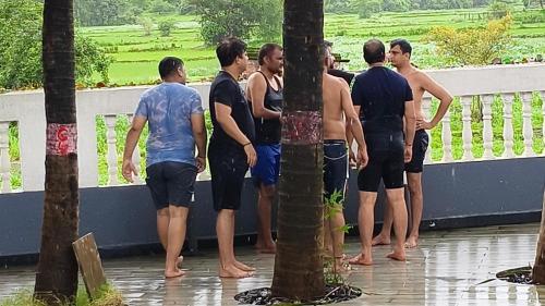 a group of men standing next to a wall in the rain at Bendre's Farm Stay-Neral in Neral