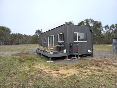 a gray tiny house parked in a field at Redman View Luxury Lakeside Cabin in Lake Fyans