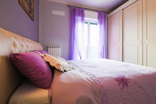 a bedroom with a bed with purple curtains and a window at Villamir B&B in Albenga