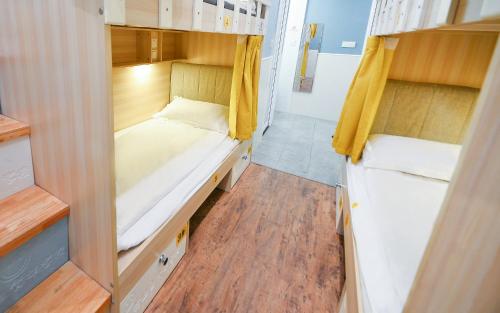 a small room with two beds and wooden floors at 笑脸里青年旅舍锦里店 in Chengdu