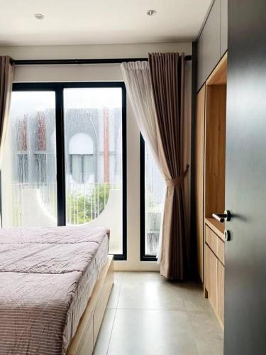 Un dormitorio con una cama y una ventana grande. en Modern 2BR Freja Suites Near ICE BSD and AEON, en Samporo