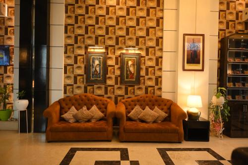 two orange chairs in a room with portraits on the wall at The Vaishnavi in Deoghar