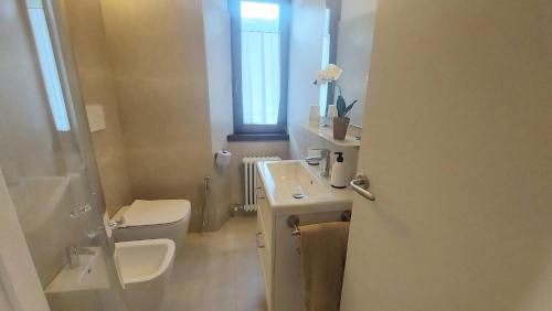 a bathroom with a sink and a toilet and a window at Appartamento Nena in Tenno