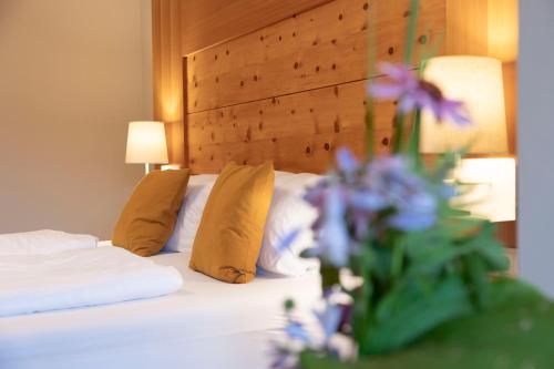 a bedroom with a bed with pillows and a vase of purple flowers at Apart-Elisabeth in Mieming