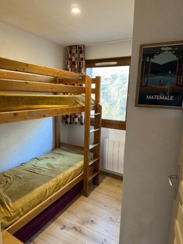 une chambre avec deux lits superposés et une fenêtre dans l'établissement Appartement T3 cosy refait à neuf avec vue lac et montagnes et avec garage, aux Angles