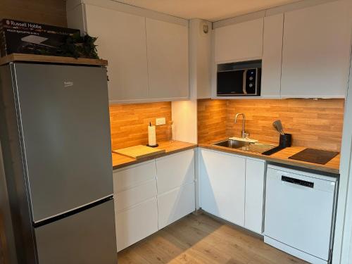 une cuisine avec des armoires blanches et un réfrigérateur en acier inoxydable dans l'établissement Appartement T3 cosy refait à neuf avec vue lac et montagnes et avec garage, aux Angles