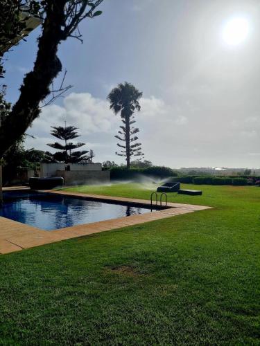 a swimming pool in a grassy yard with a bench at Villa Mazagan de luxe 6 chambres face mer 1000m2 in El Jadida