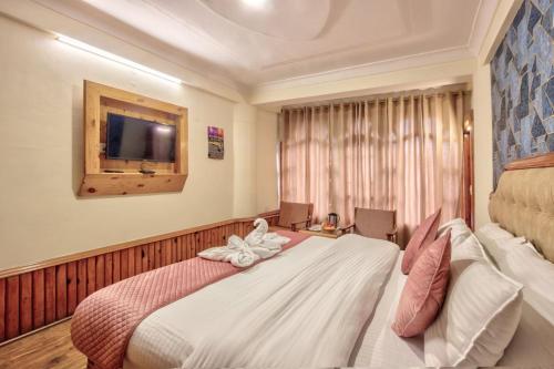 a hotel room with a bed with a towel on it at Hotel Ibex in Manāli