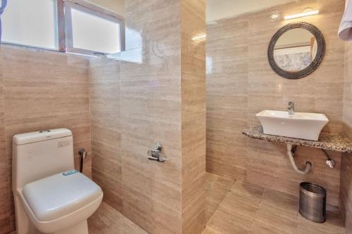 a bathroom with a toilet and a sink at Hotel Ibex in Manāli