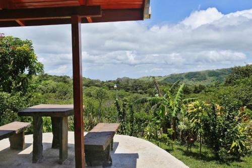 a table and benches on a porch with a view of the mountains at Cabañas La Pradera in Monteverde Costa Rica