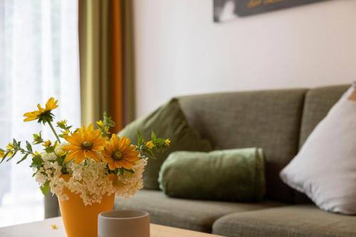 a vase with flowers on a table in front of a couch at Apart-Elisabeth in Mieming