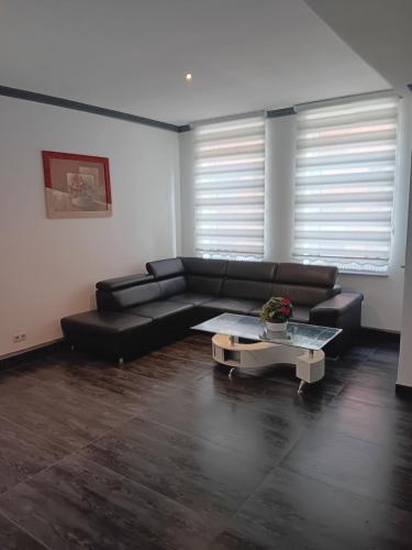 a living room with a black leather couch and a table at HafenApartement in Bremerhaven
