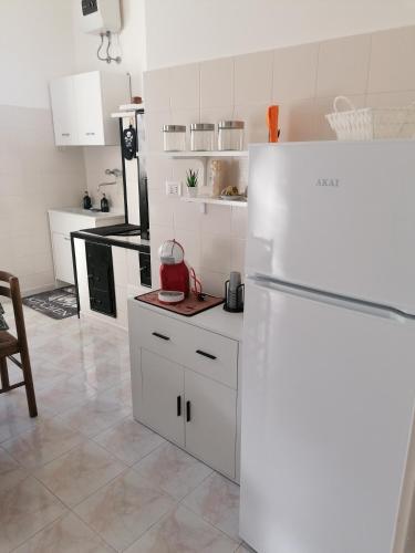 a white kitchen with a refrigerator and a table at La casa dei fiori in Nociglia