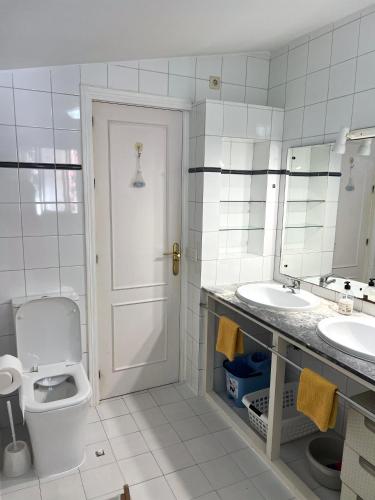 a white bathroom with a toilet and two sinks at Elviria Beachside House Marbella in Marbella