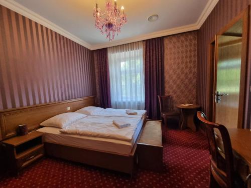 a hotel room with a bed and a chandelier at Pałac Lucja BB in Zakrzów