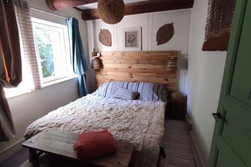 une chambre avec un lit avec une tête de lit en bois et une fenêtre dans l'établissement la maison aux volets vert, à Chaméane