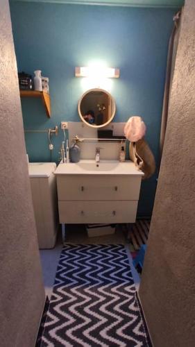 une salle de bain bleue avec un lavabo et un miroir dans l'établissement la maison aux volets vert, à Chaméane