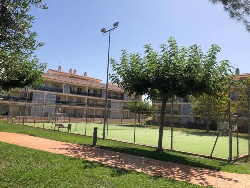 a tennis court in front of a building at Apartamento con vista al mar in Sant Jordi