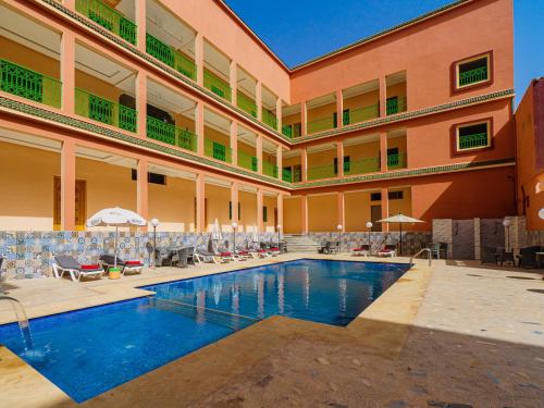 a large building with a swimming pool and chairs at HOTEL LA VALLEE DES KASBAHS CHEZ ILYAS in Tinerhir