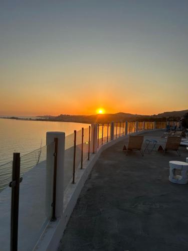 a pier with chairs and the sun setting over the water at Villa Mare Di Montelusa in Agrigento