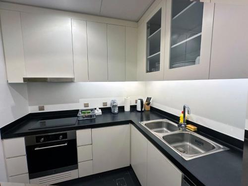 リヤドにあるبرج داماك الرياض DAMAC Towers Riyadhの白いキャビネットとシンクのあるキッチン