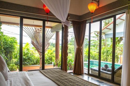 a bedroom with a bed and large windows and a pool at Phong Nha Farmstay in Phong Nha