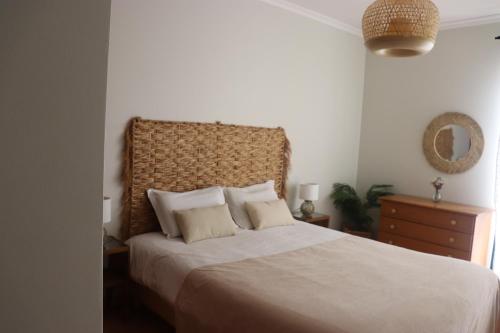 a bedroom with a large bed with a large headboard at Pé n' Areia Beach House Porto Santo in Porto Santo