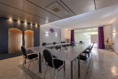 a large dining room with a long table and chairs at The Originals City, Hôtel de Bordeaux, Bergerac centre in Bergerac