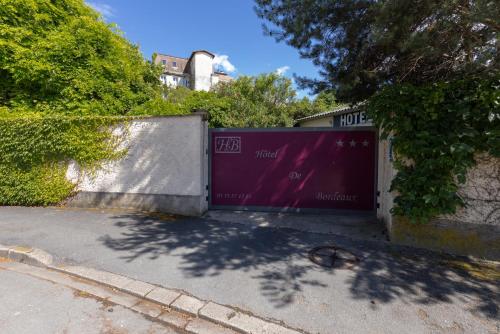 a garage with a purple door on the side of a street at The Originals City, Hôtel de Bordeaux, Bergerac centre in Bergerac