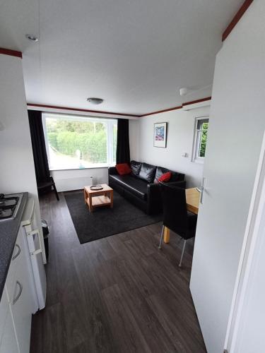 a living room with a couch and a table at Chalet dichtbij zee en duinen in Heemskerk