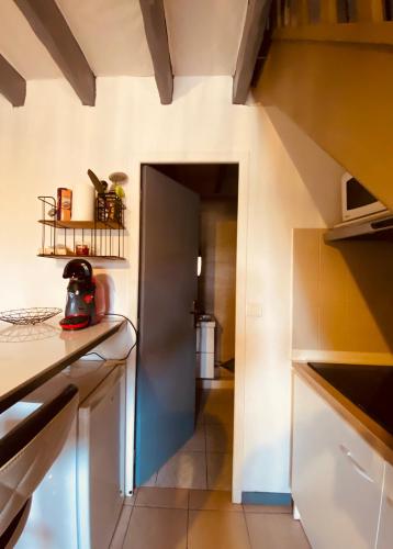 une cuisine avec un couloir menant à une cuisine avec des armoires blanches dans l'établissement Le cocon de Lormont, à Lormont