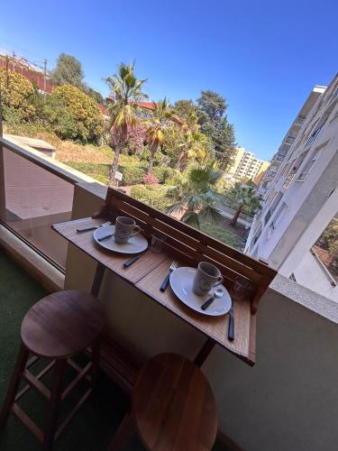 une table avec deux tasses et soucoupes devant une fenêtre dans l'établissement 2 pièces,à 4 min a pieds de la mer, à Cagnes-sur-Mer