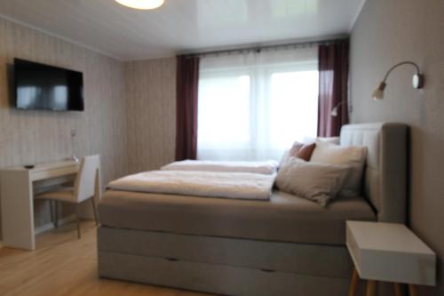 Schlafzimmer mit einem Bett, einem Fenster und einem Schreibtisch in der Unterkunft STRANDLIEBE 100 qm Gartenwohnung (eingezäunt), 15 Gehminuten zum Strand in Neukirchen