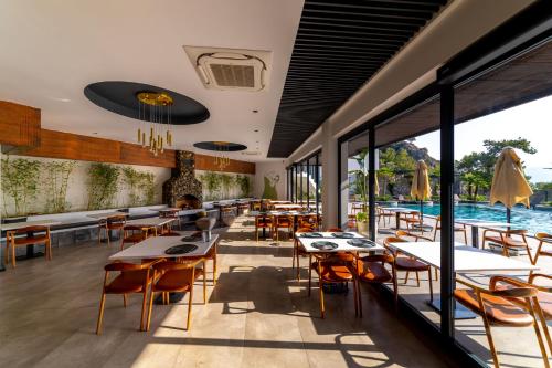a restaurant with tables and chairs and a pool at Ramitos Hotel in Turunc