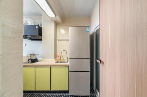 a kitchen with a refrigerator and a sink at Guangzhou He She Art Apartment in Guangzhou