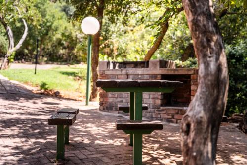 a picnic table and two benches in a park at ATKV Klein-Kariba in Bela-Bela