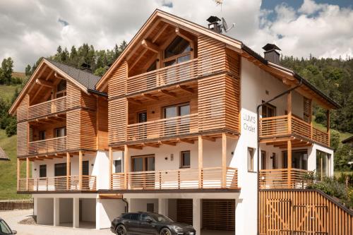 a wooden house with a car parked in front of it at Chalet Lumis in San Vigilio Di Marebbe